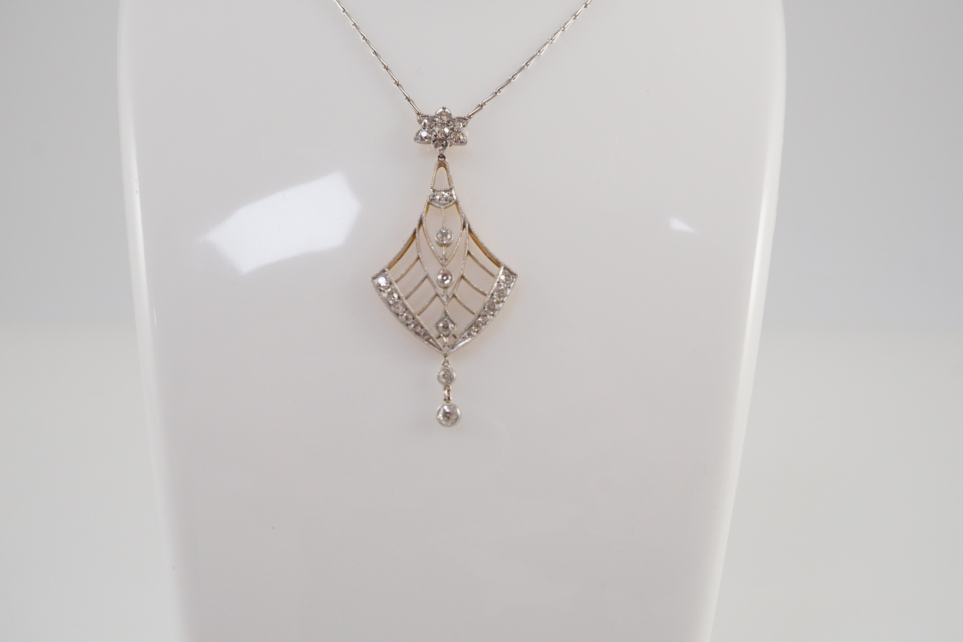 An early to mid 20th century pierced platinum, gold and millegrain set diamond cluster drop pendant